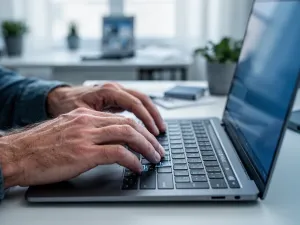 Dłonie piszące na klawiaturze nowoczesnego laptopa w minimalistycznym biurze, ilustrujące pracę z systemem Windows 11.